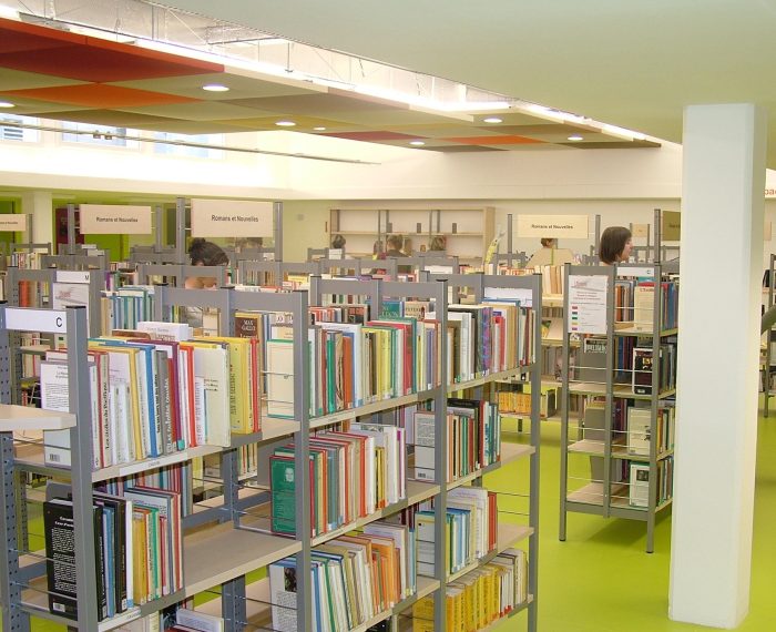 Vue d'une partie de la salle de lecture des adultes avec des étagères de livres et un sol vert